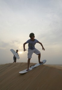 Our Boy sandboarding in Liwa, surrounded by desert